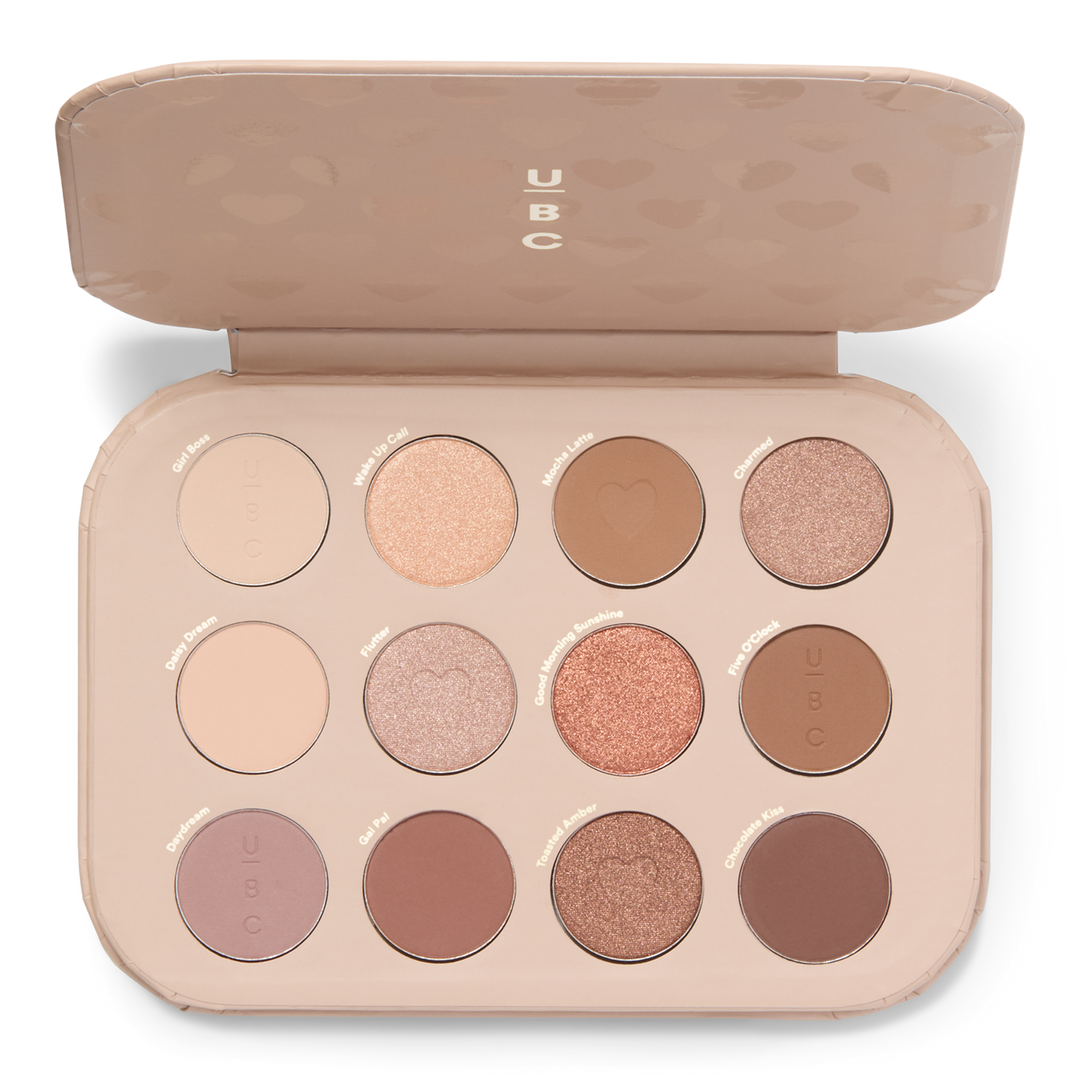 A makeup palette featuring 12 eyeshadow shades in a range of neutral and warm tones, including matte and shimmer finishes, each labeled with names.
