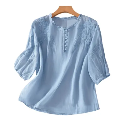Light blue blouse with floral embroidery on the chest and sleeves, featuring a round neckline with button details and three-quarter length sleeves.