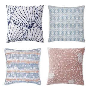 Four decorative pillows with varying designs: striped, snowflake, abstract, and floral patterns.
