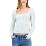 A person is wearing a light blue, long-sleeve top with a floral pattern and square neckline, paired with blue jeans.