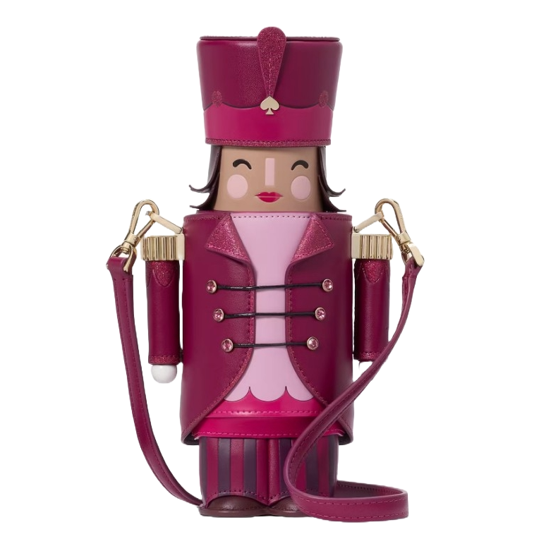 A whimsical crossbody bag designed to resemble a nutcracker, featuring a magenta and pink color scheme, a face with a smiling expression, a decorative uniform, and detachable shoulder straps.