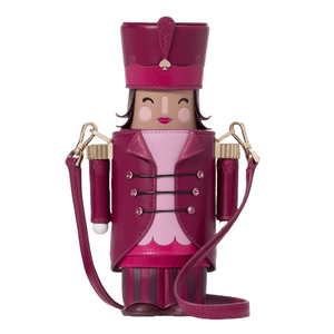 A whimsical crossbody bag designed to resemble a nutcracker, featuring a magenta and pink color scheme, a face with a smiling expression, a decorative uniform, and detachable shoulder straps.