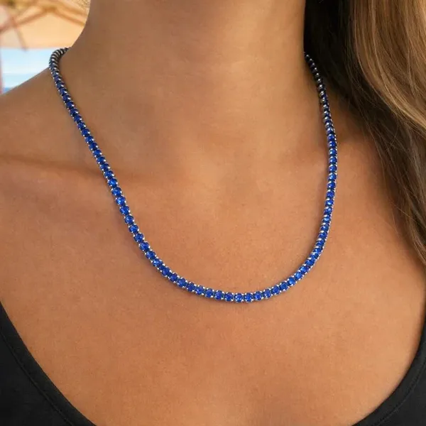 A person is wearing a sapphire blue beaded necklace, complemented by a black top.