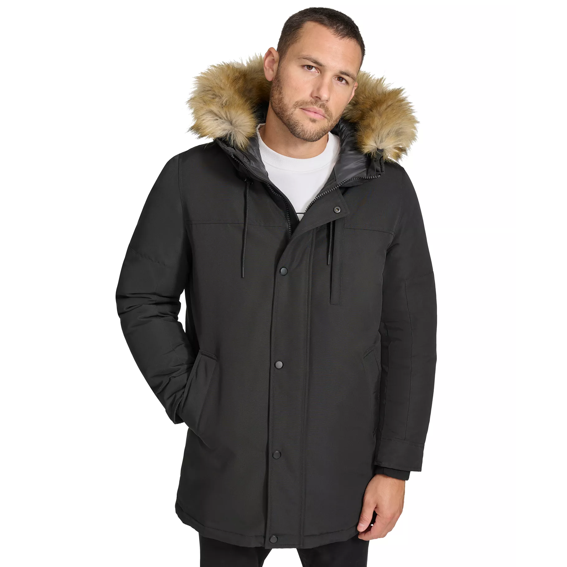 A man wearing a black parka with a faux fur-lined hood stands with his hands in the pockets. The jacket features a button-up front and drawstring adjusters.