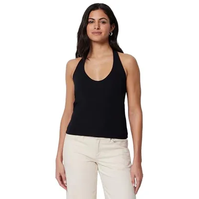 A woman wearing a black halter top paired with beige pants.
