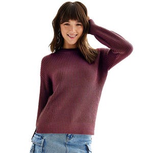 A woman is wearing a purple ribbed sweater paired with denim jeans.