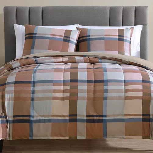 A plaid-patterned comforter set with matching pillows on a bed with a gray upholstered headboard. The design features various shades of brown, white, and blue.
