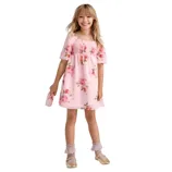 Girl wearing a pink floral dress with puff sleeves, paired with lace-trimmed socks and gold shoes. She holds a matching floral purse.