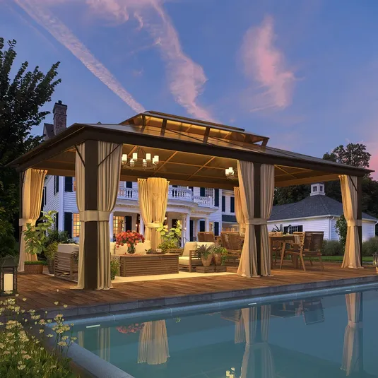A 20-foot aluminum patio gazebo with open sides, cream curtains, and outdoor seating, situated on a wooden deck by a pool, featuring a chandelier and surrounded by plants.