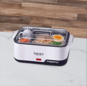 A portable electric lunch box with a transparent lid containing cooked rice, boiled egg, and vegetables. Branding shows \“bentō PRESTO\“.