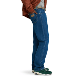 A person wearing blue straight-leg jeans, a brown jacket, and green and white sneakers.