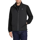 A man is wearing a black softshell jacket with a front zipper and a small logo on the chest, paired with dark jeans.