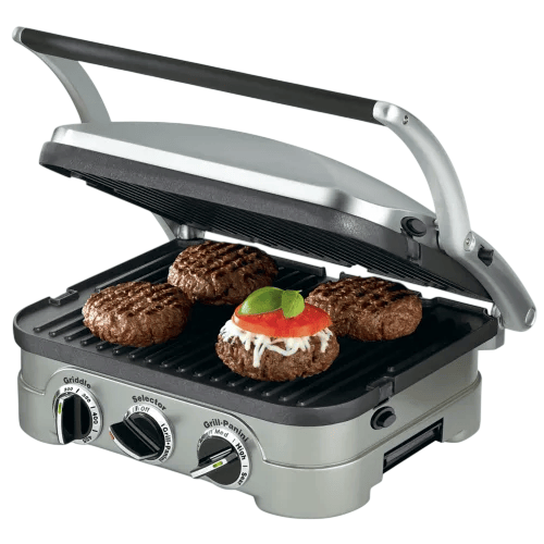 A countertop grill with adjustable settings is cooking four burger patties, one topped with cheese, tomato, and basil.