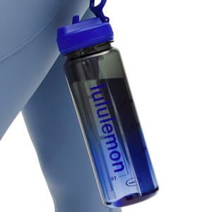 A transparent blue water bottle with a blue screw-on cap, featuring the \“lululemon\“ logo vertically. It has measurement markings on the side for tracking liquid intake.