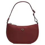 A small, maroon handbag with an adjustable strap and a metal emblem on the front. The bag features a zipper closure and a detachable hook.