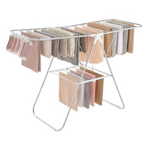 A foldable drying rack displaying a variety of towels and fabrics in neutral and pastel shades.
