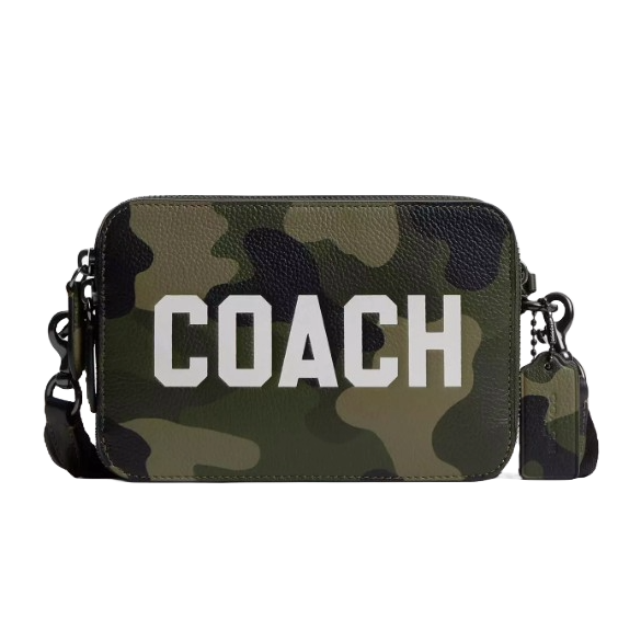 A rectangular crossbody bag with a camouflage pattern, featuring the word \“Coach\“ in large white letters, and a detachable strap.