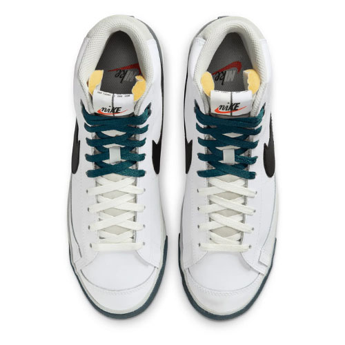 A pair of white Nike sneakers with navy and light green accents, viewed from above.