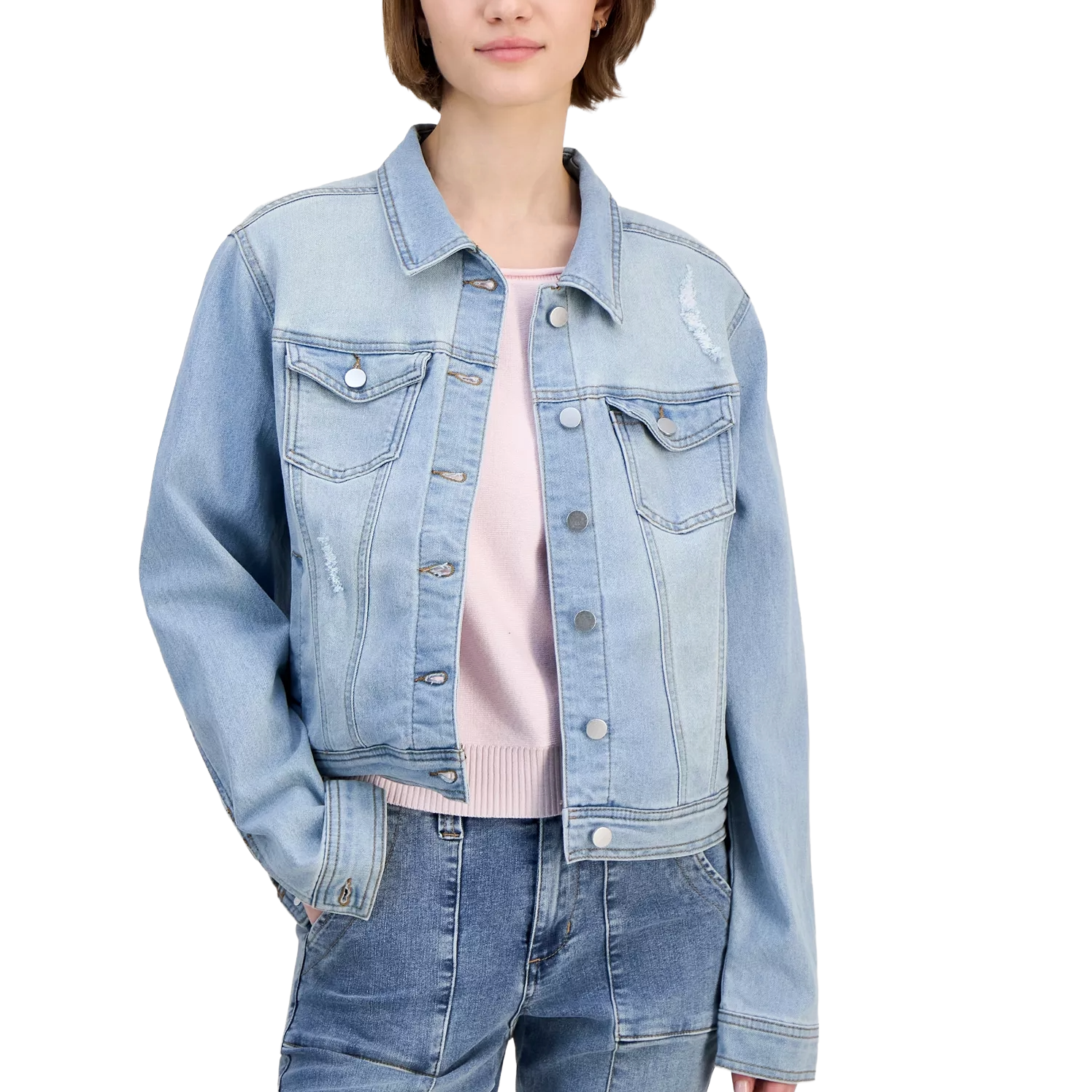 A person wears a light blue denim jacket with front buttons and pockets, paired with a light-colored sweater and blue jeans.