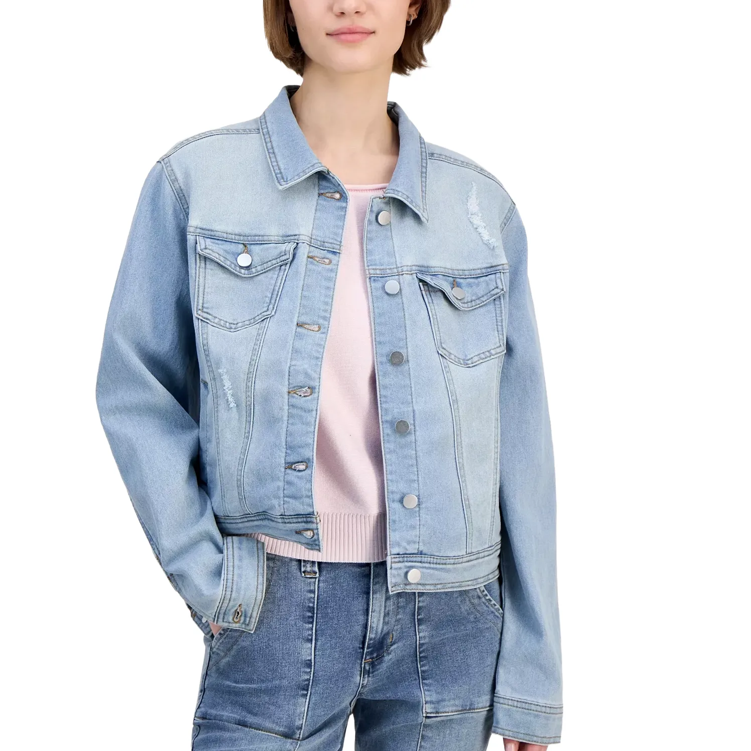 A person wears a light blue denim jacket with front buttons and pockets, paired with a light-colored sweater and blue jeans.