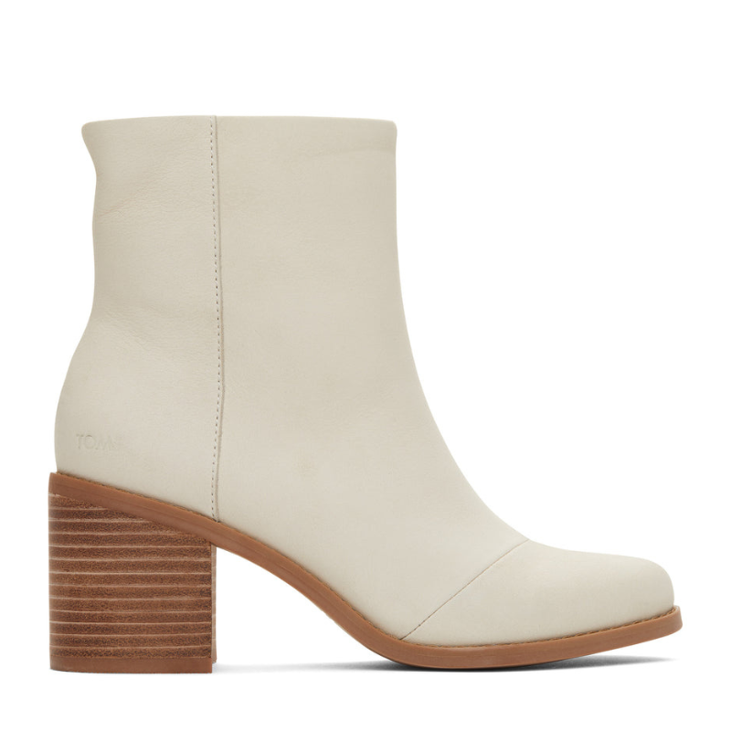 TOMS Evelyn Heeled Boot is a sleek, cream-colored ankle boot with a smooth leather upper, featuring a stacked wooden block heel. Designed for versatility and style, it offers a minimalist silhouette with subtle stitching details.