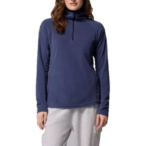 A woman is wearing a navy-blue long-sleeve fleece pullover with a half-zip collar, paired with light gray sweatpants.