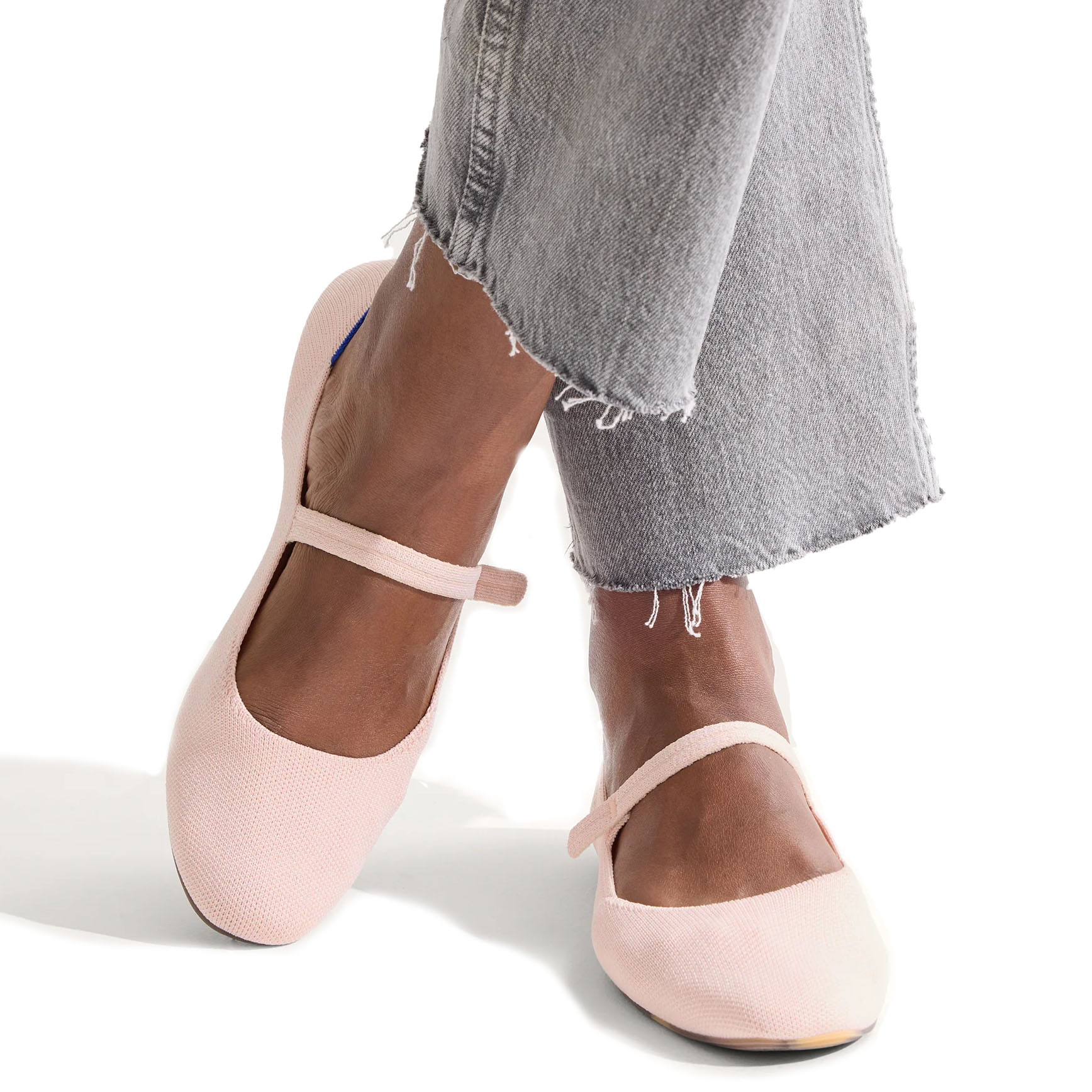 Rothy's Square Mary Jane features a blush pink color with a textured fabric finish and an elastic strap across the top. The shoes have a rounded square toe and are styled with frayed hem jeans.