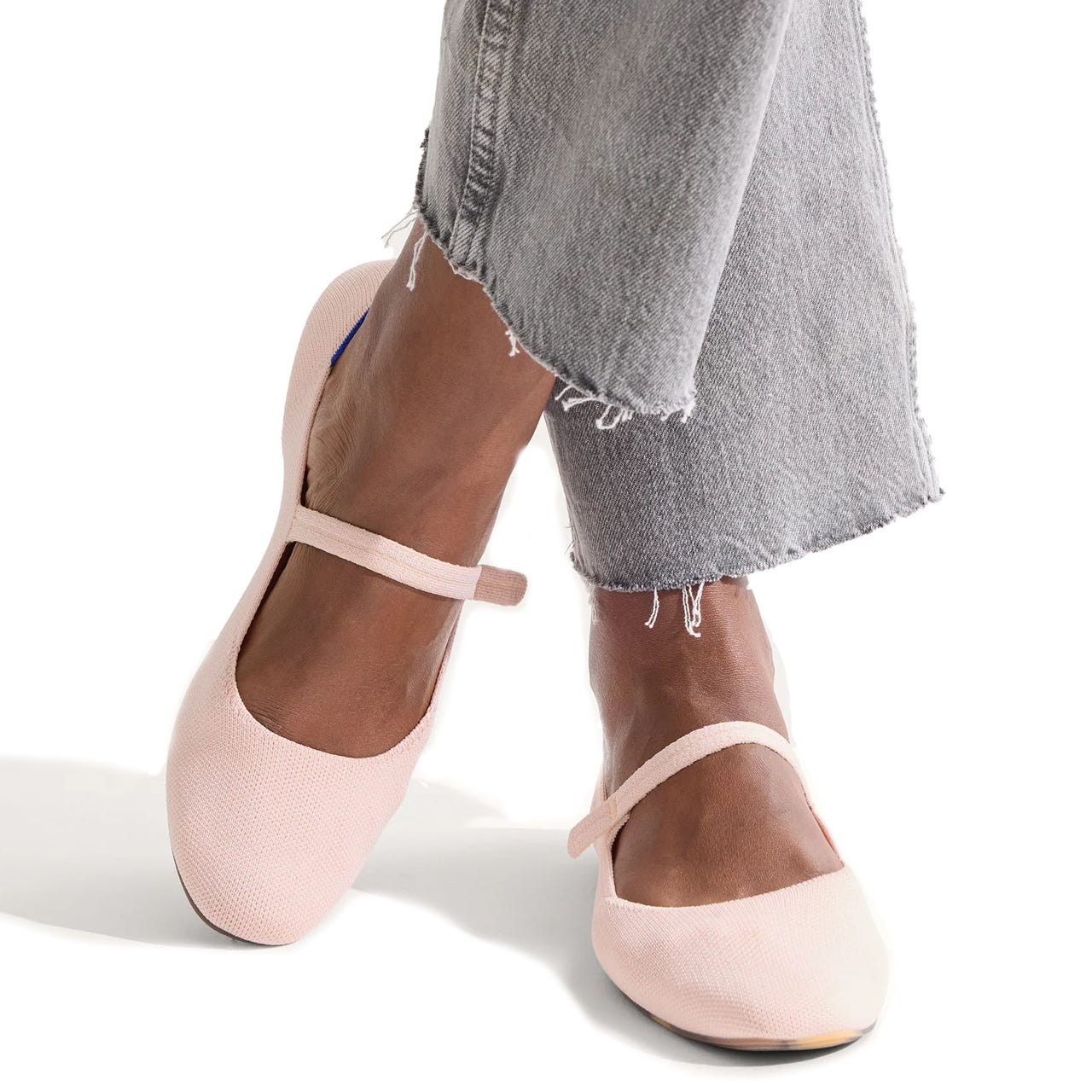 Rothy's Square Mary Jane features a blush pink color with a textured fabric finish and an elastic strap across the top. The shoes have a rounded square toe and are styled with frayed hem jeans.