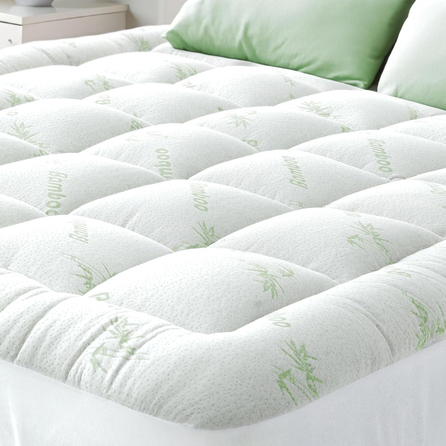 A quilted bamboo mattress topper enhances comfort with its padded design, featuring green bamboo patterns on a white surface, paired with matching green pillows.