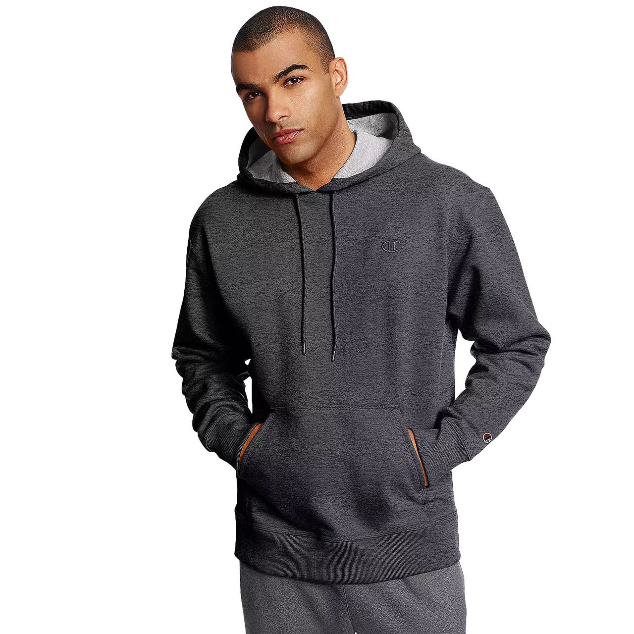 The Champion Powerblend Fleece Hoodie is a dark gray pullover with a drawstring hood, a front kangaroo pocket, and a small embroidered logo on the chest. It features ribbed cuffs and hem for a comfortable fit.