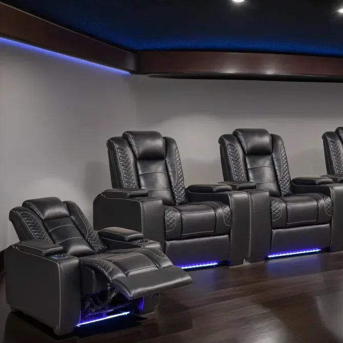 A row of black leather reclining theater chairs with quilted patterns, cup holders, and LED lighting underneath, ideal for a home theater setup.