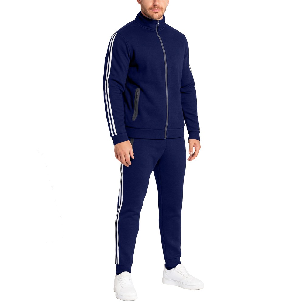 A man is wearing a navy blue tracksuit with white stripes along the sleeves and pants, paired with white sneakers.