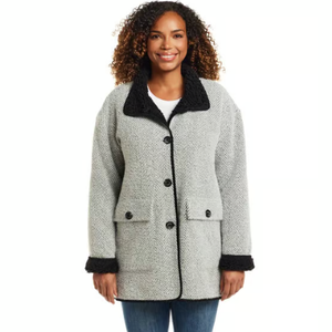 A woman is wearing a gray herringbone coat with black accents on the collar and cuffs. The coat features black buttons and flap pockets.