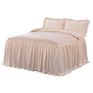 A luxurious bed ensemble featuring a pink spread with a ruffled skirt, matching ruffled pillowcases, and a comforter with button details.