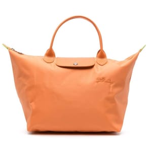 Orange Longchamp Le Pliage M Top Handle Bag with a minimalistic design, featuring a snap button closure, short handles, and a subtle embossed logo.