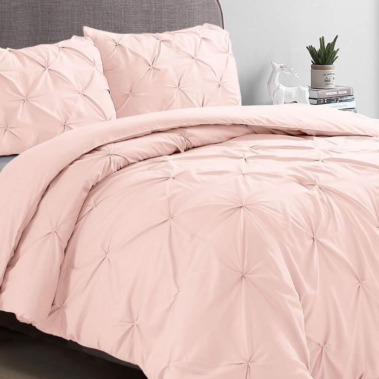 A king-size pintuck blush comforter set featuring an elegant gathered design, including a comforter and matching pillow shams. The bedding is soft pink and adds a touch of elegance and comfort to any bedroom decor.