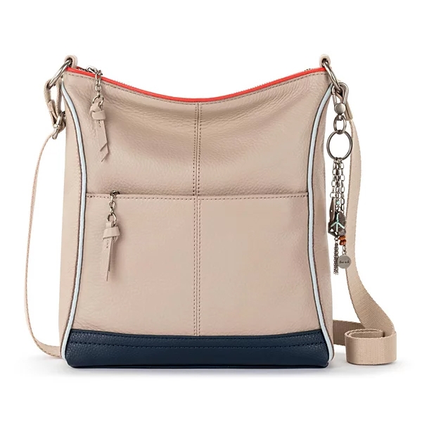 A beige and navy leather crossbody bag with a red lining, featuring two zipper accents and a decorative keychain attachment.