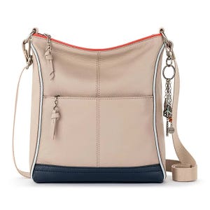 A beige and navy leather crossbody bag with a red lining, featuring two zipper accents and a decorative keychain attachment.