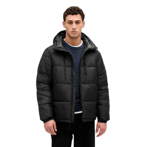 A man is wearing a black, quilted puffer jacket with a hood, over a dark blue sweatshirt.