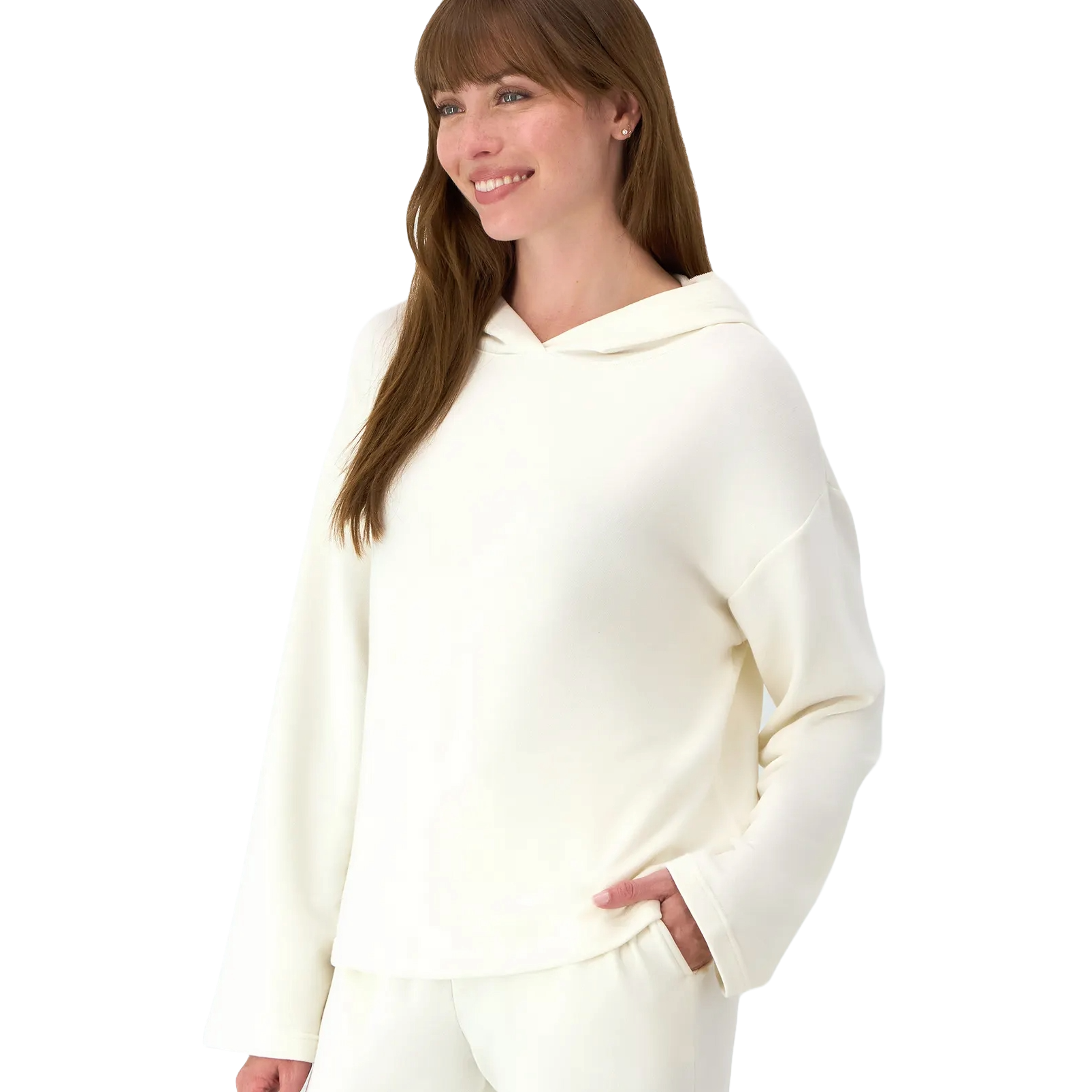 A woman wearing a hooded, long-sleeve, off-white top paired with matching pants. She’s smiling and has her right hand in her pocket.