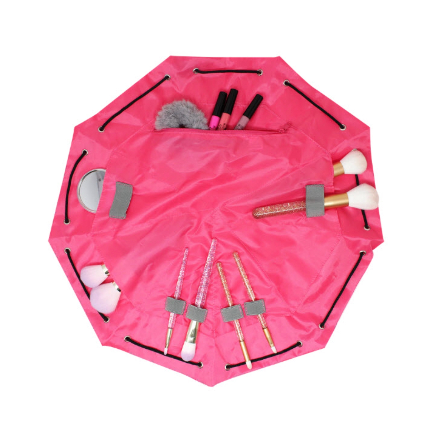 A pink toiletry cinch bag with multiple compartments holds various makeup items, including brushes, lip products, and a compact mirror. The bag features a drawstring closure for easy packing.