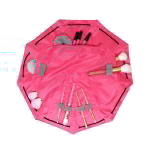 A pink toiletry cinch bag with multiple compartments holds various makeup items, including brushes, lip products, and a compact mirror. The bag features a drawstring closure for easy packing.