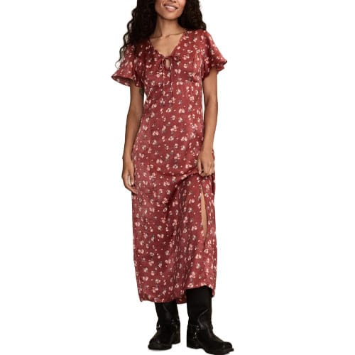 A woman wears a red floral maxi dress with a slit and flutter sleeves, paired with black boots.