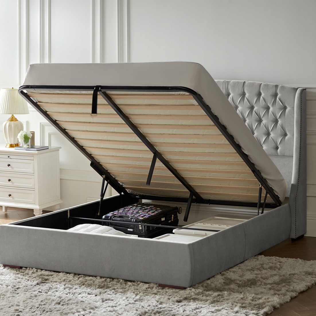 Queen Hydraulic-Lift Storage Bed with a tufted headboard and under-bed storage, featuring a mattress platform lifted by pistons. Ideal for maximizing space and organizing items like suitcases and blankets.