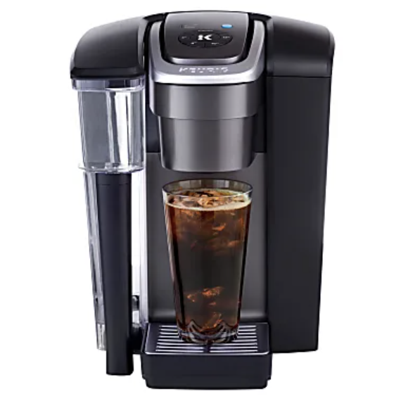 A single-serve coffee maker dispensing iced coffee into a tall glass, featuring a removable water reservoir and a sleek black design.