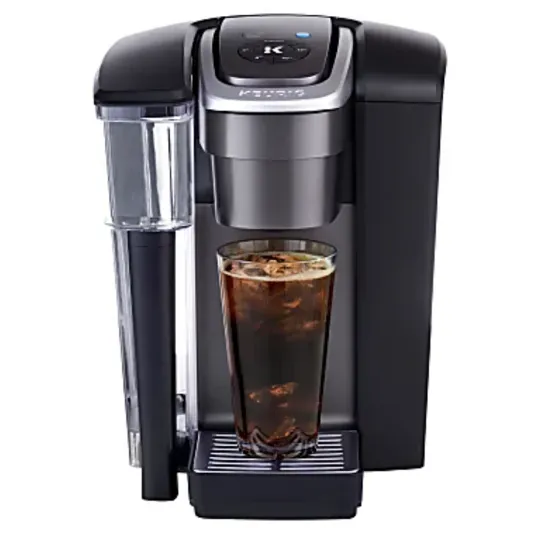 A single-serve coffee maker dispensing iced coffee into a tall glass, featuring a removable water reservoir and a sleek black design.