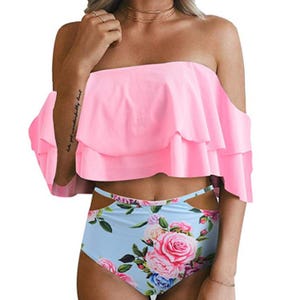A swimsuit featuring a pink, off-the-shoulder ruffled top and high-waisted floral bottoms with a blue background and rose designs.