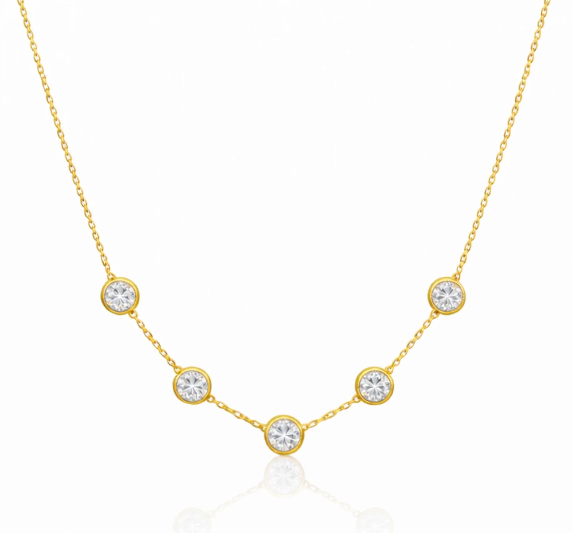 A delicate gold necklace featuring five evenly spaced, circular settings with clear gemstones on a fine chain.
