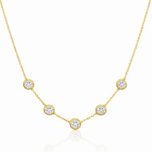 A delicate gold necklace featuring five evenly spaced, circular settings with clear gemstones on a fine chain.