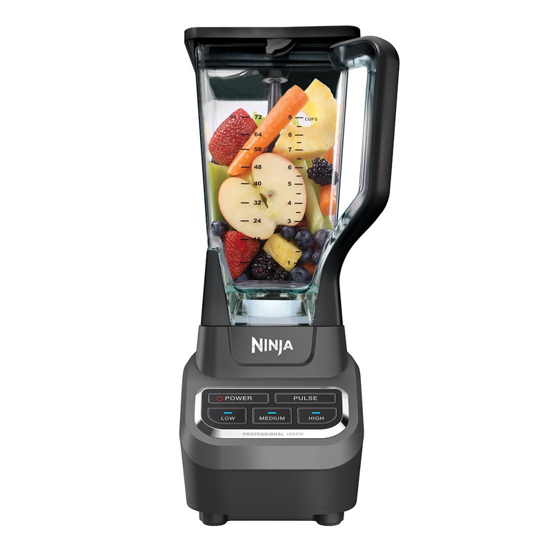 A Ninja blender featuring a transparent container filled with assorted fruits and vegetables, including strawberries, apples, pineapples, and blueberries. The blender has power, pulse, and speed settings (low, medium, high).